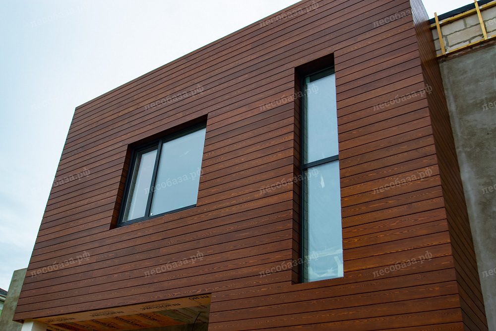 Фасад дома обшитый скошенный планктом из лиственницы с покраской лаком Teknos